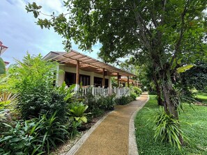 A covered outdoor area with a pathway leading to a building with a porch.