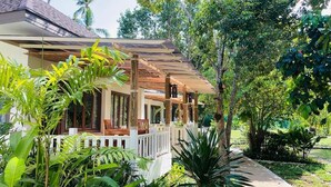 A covered outdoor area with wooden furniture and a white fence, surrounded by lush greenery. - Treeya Lanta (Ko Lanta)