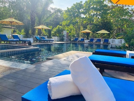 Una piscina al aire libre, sombrillas, sillones reclinables de piscina