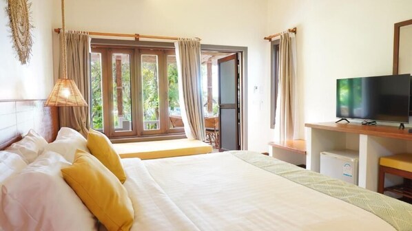 A hotel room with a bed, a television, a desk, and a window with curtains.