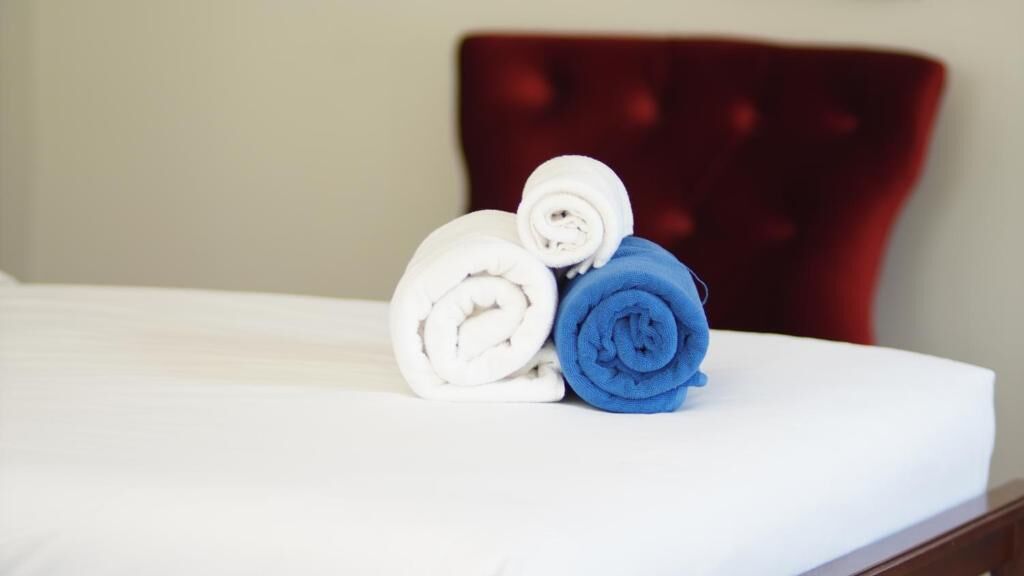Una cama bien hecha con toallas enrolladas en blanco y azul.