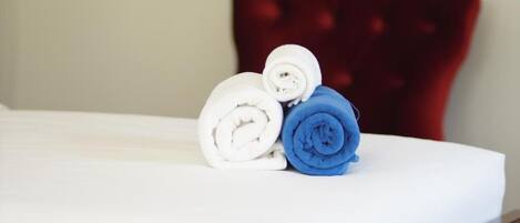 Una cama bien hecha con toallas enrolladas en blanco y azul.
