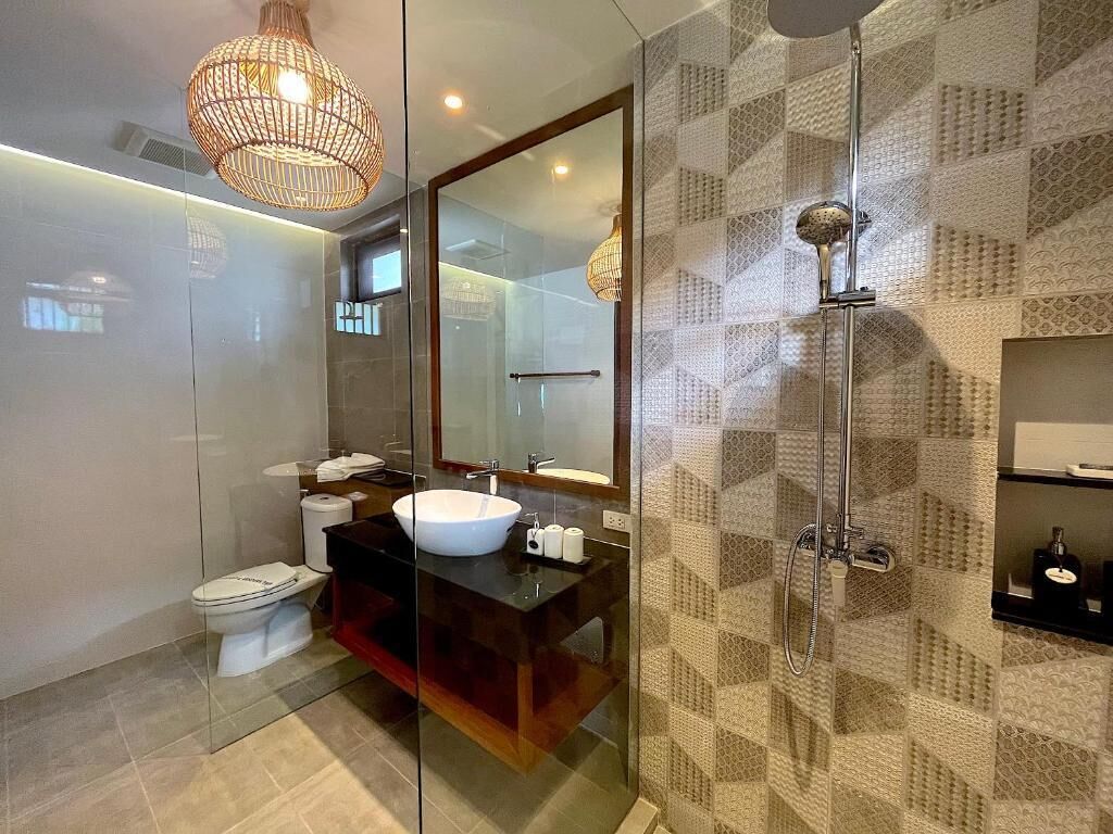 A modern bathroom with a glass-enclosed shower, a large mirror, and a white sink.