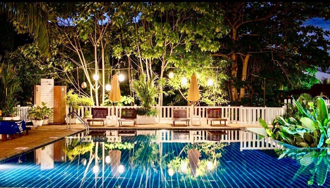 Una piscina al aire libre, sombrillas, sillones reclinables de piscina