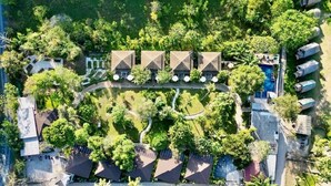 An aerial view of a resort with multiple bungalow-style buildings, a central swimming pool, and surrounding lush greenery. - Treeya Lanta (Ko Lanta)
