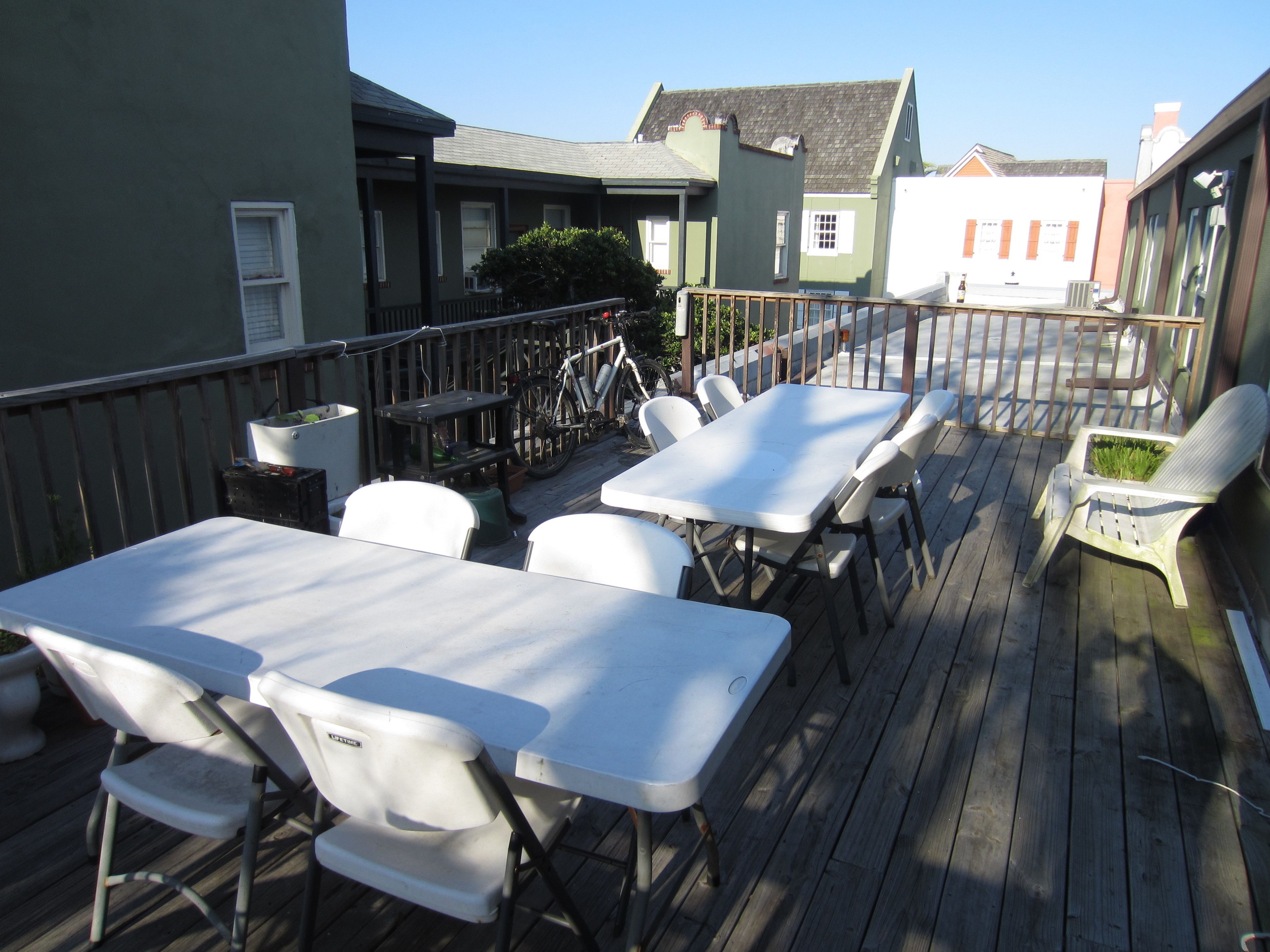 Une terrasse extérieure avec des tables et des chaises, un vélo et un petit coin jardin.