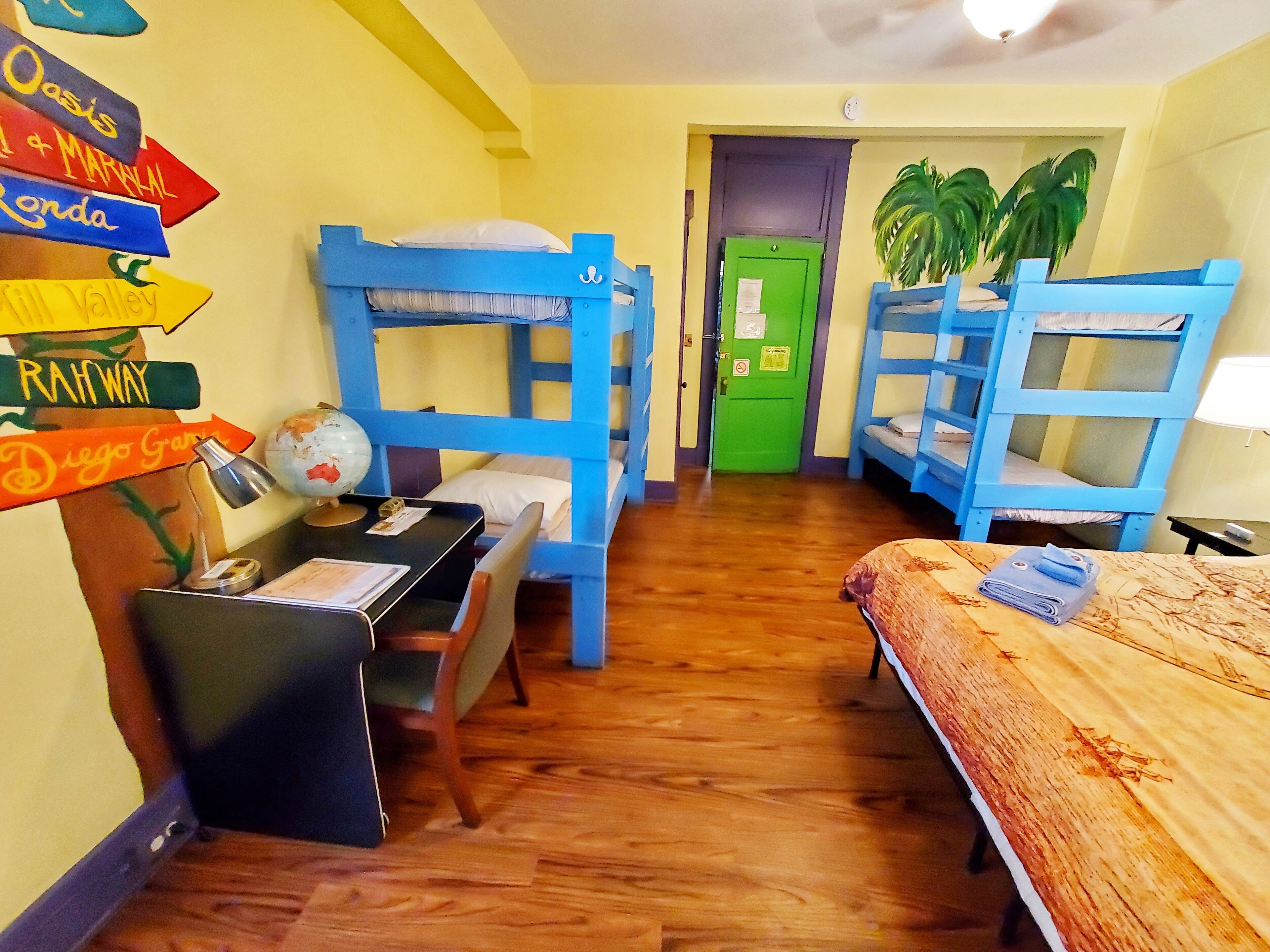 Une chambre avec des lits superposés, un bureau avec un globe terrestre et un mur orné de panneaux indicateurs.