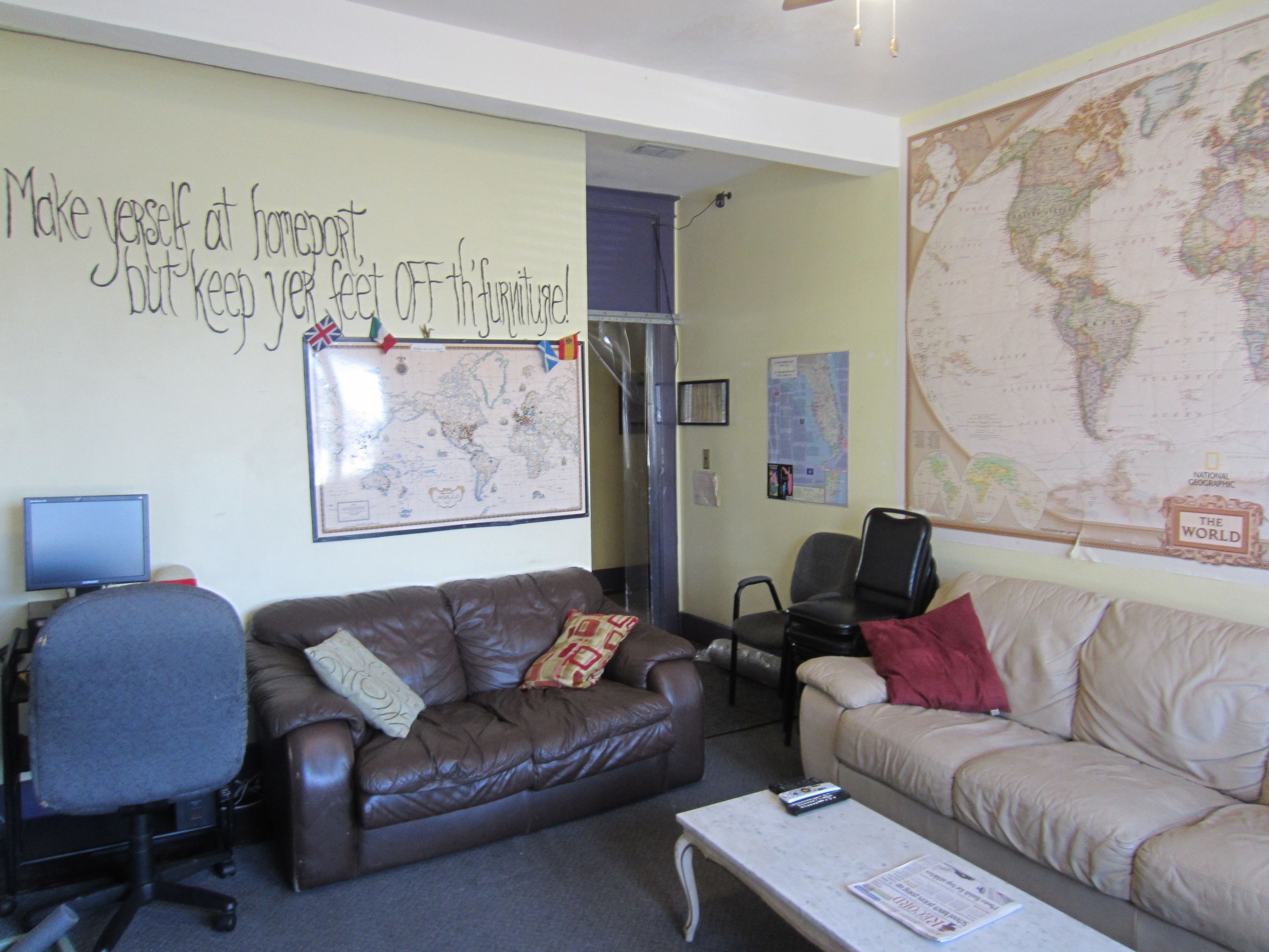 A living room with two couches, a coffee table, a TV, and a large world map on the wall.
