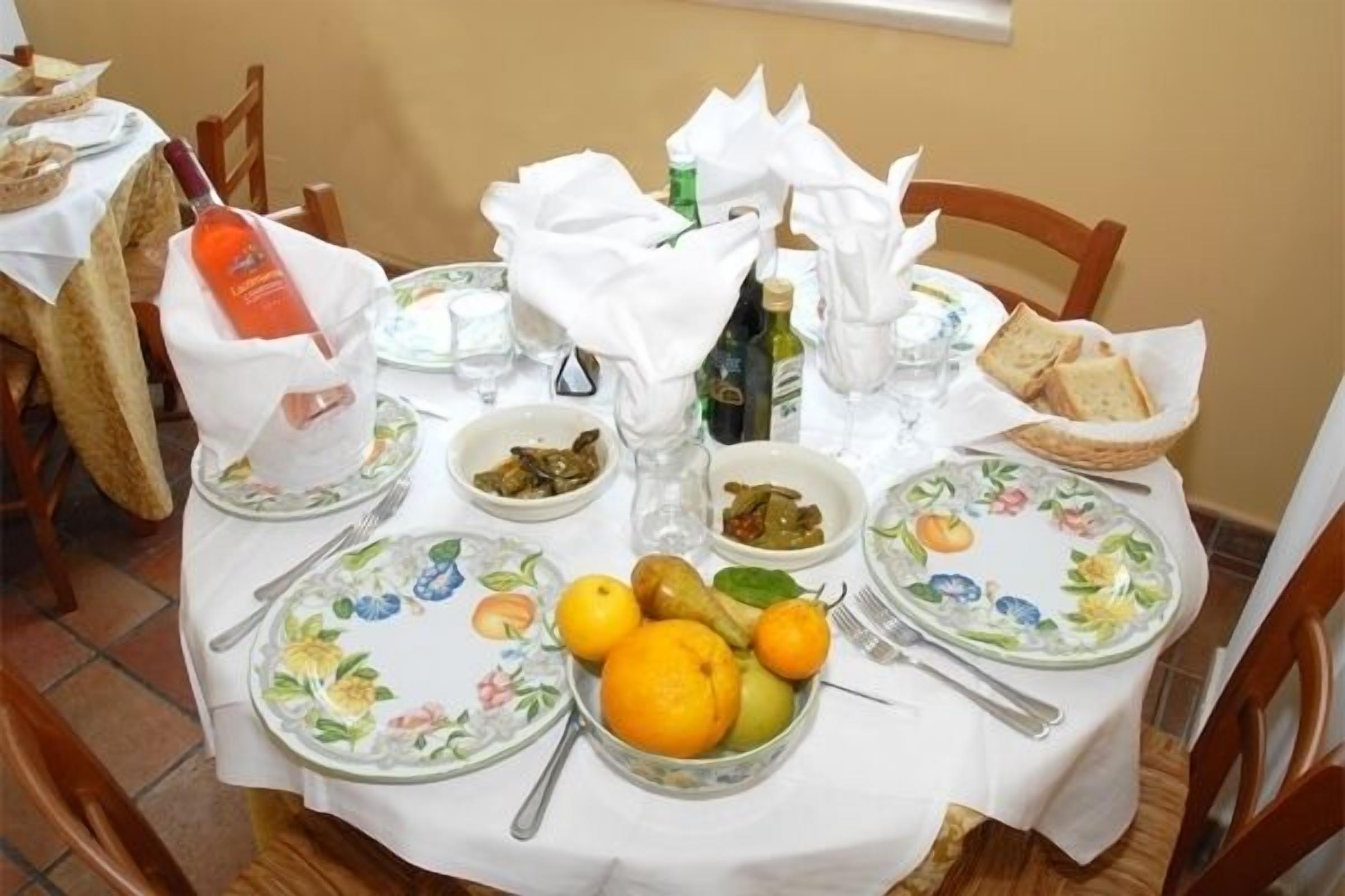 A dining table set with plates, bowls, and fruits, surrounded by chairs.