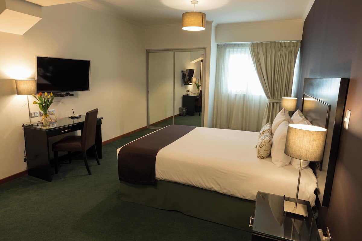 Une chambre d’hôtel équipée d’un lit, d’un bureau, d’une chaise, d’une télévision et d’un miroir.