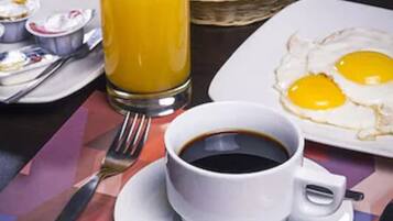 A breakfast setting with a glass of orange juice, a cup of coffee, and a plate of eggs on a table with a placemat.