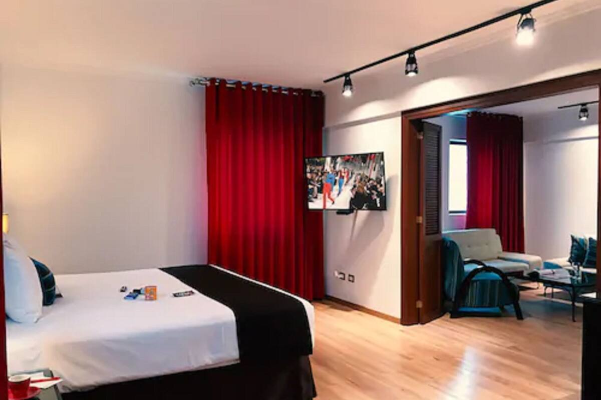 Une chambre d’hôtel avec un lit, un bureau, une chaise et un téléviseur.