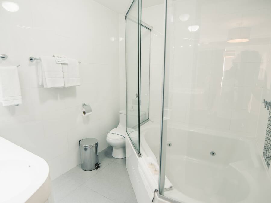 Un baño moderno con ducha envuelta en vidrio, un lavabo blanco y un inodoro.