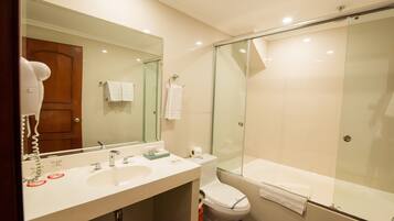 Un baño moderno con un espejo grande, dos lavamanos, un inodoro y una ducha con paredes de vidrio.