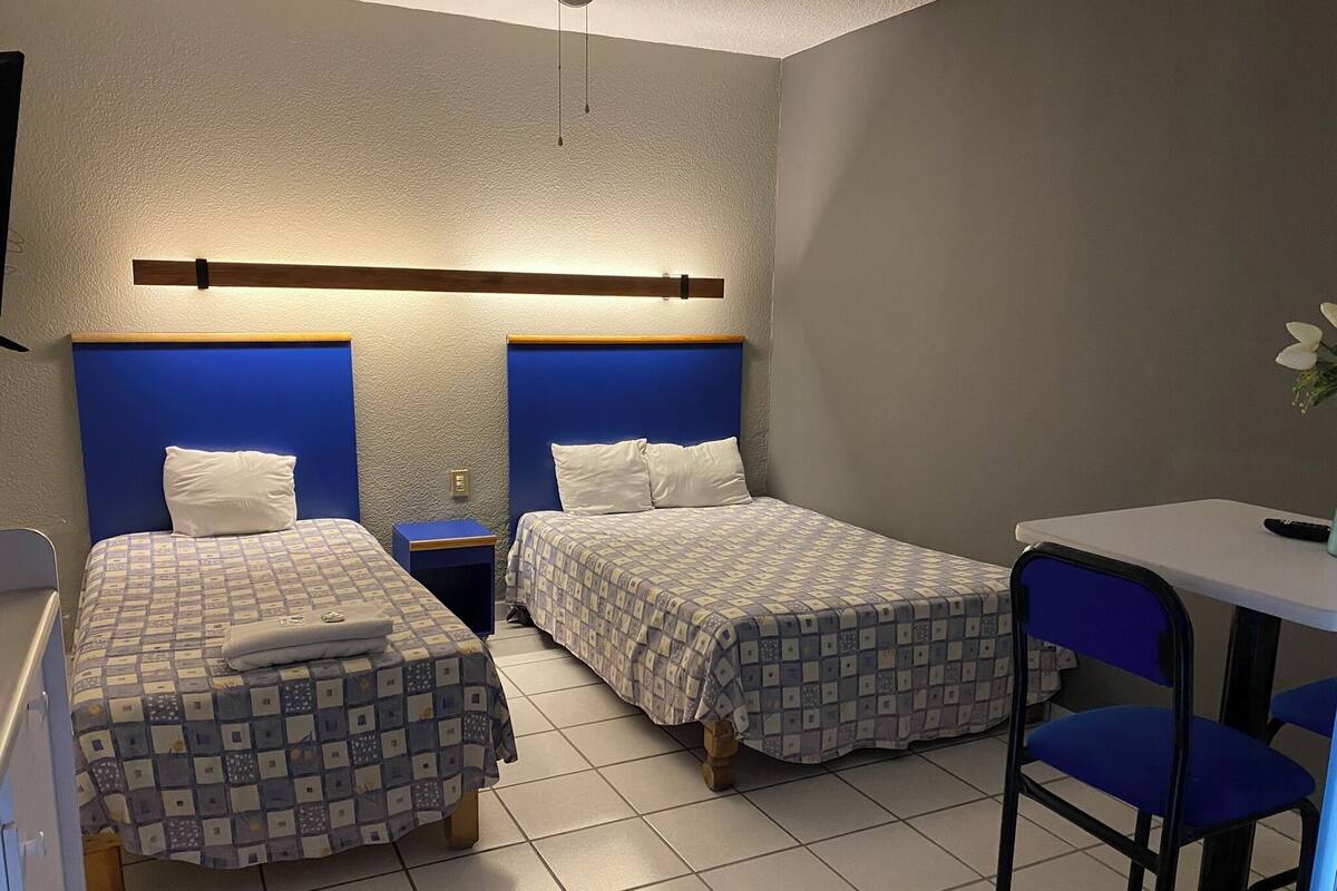 A room with two beds, a small table, and a chair.