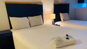A hotel room with two beds, a nightstand, and a lamp. - Hotel H Américas Guadalajara (Guadalajara)