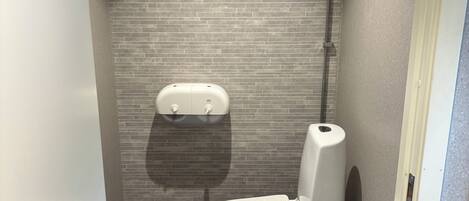 A small, modern bathroom with a toilet and a hand dryer mounted on the wall.