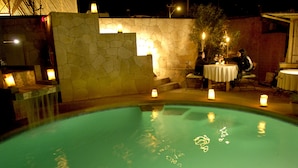 Una piscina al aire libre, sombrillas, sillones reclinables de piscina