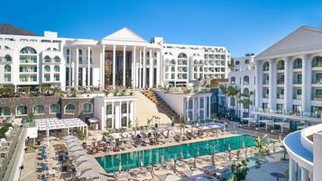 Un hotel con una piscina amplia, varios balcones y una entrada imponente.