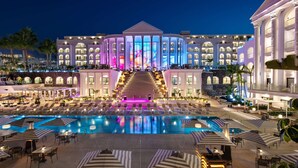Un grand hôtel doté d’une piscine centrale, de nombreux balcons et d’une entrée imposante.