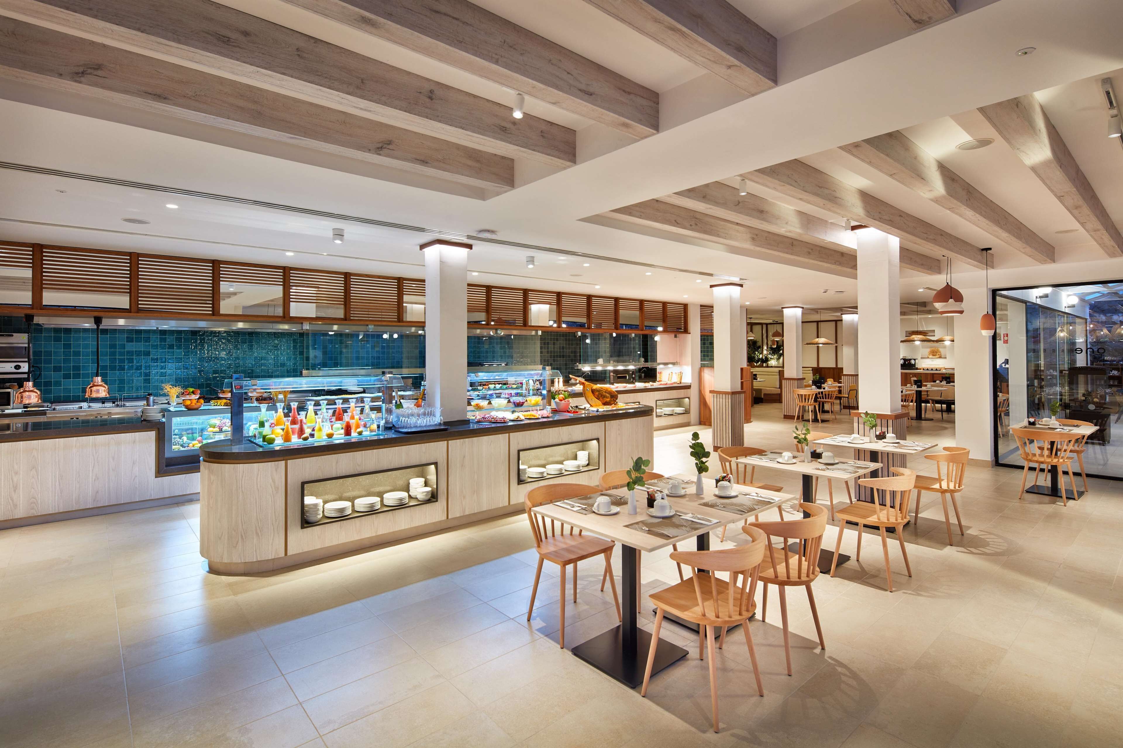 Un restaurante moderno con una barra central, vigas de madera en el techo y un diseño abierto y luminoso.