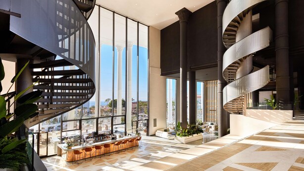 Un intérieur moderne avec un escalier en colimaçon central, de grandes fenêtres et un coin bar.