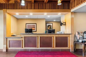 Un comptoir d’accueil avec deux ordinateurs, des œuvres d’art encadrées accrochées au mur et un tapis rouge.
