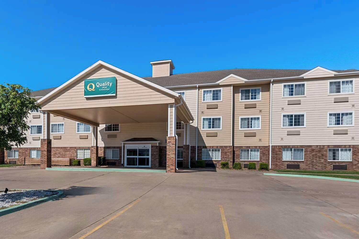 A hotel with a covered entrance, multiple windows, and a brick facade.