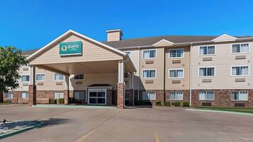 A hotel with a covered entrance, multiple windows, and a brick facade.