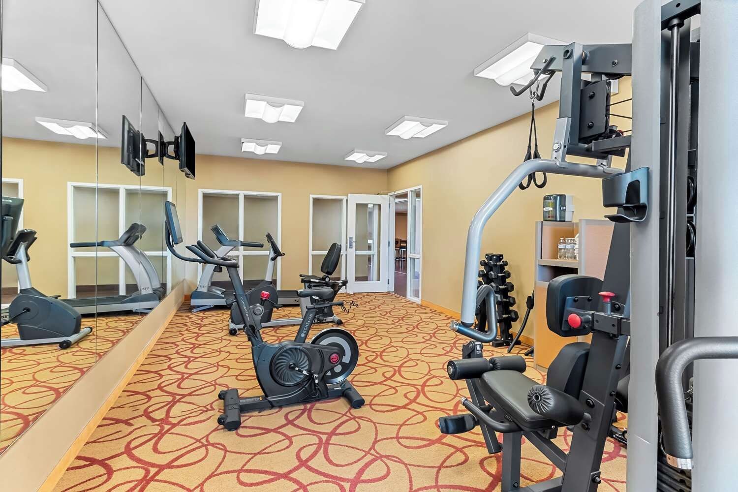 A gym with cardio machines, weightlifting equipment, and mirrors.
