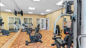 A gym with cardio machines, weightlifting equipment, and mirrors.