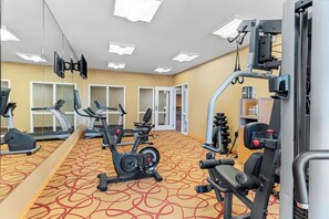 Une salle de sport équipée de machines de cardio, de matériel de musculation et de miroirs.