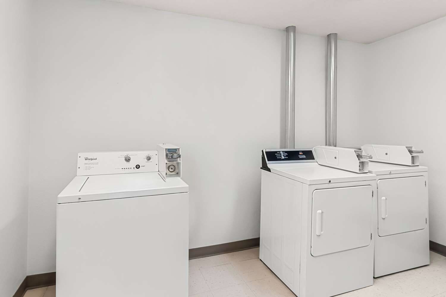 Un cuarto de lavandería con lavadora de carga frontal y una lavadora y secadora apiladas.