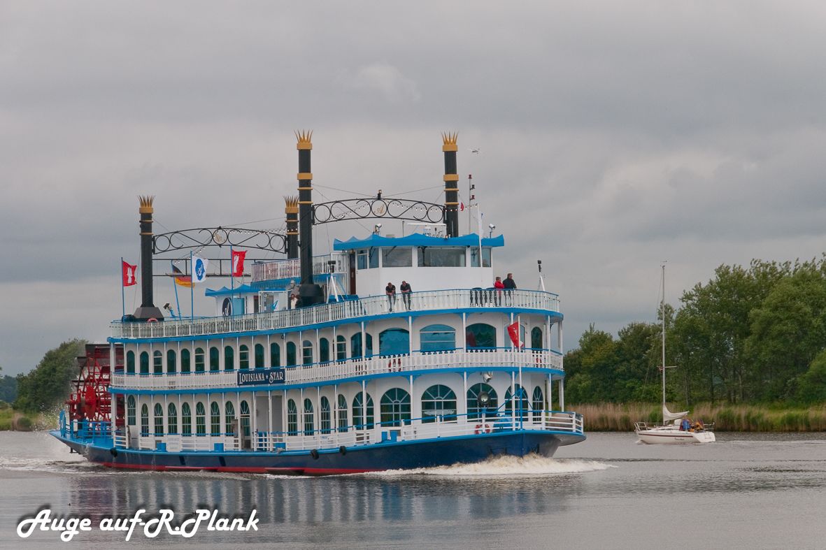 Un gran barco de recreo fluvial con varias cubiertas y una estructura de chimenea destacada.