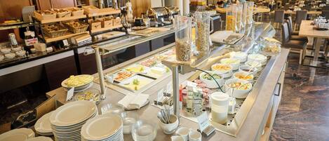 A buffet setup with various food items and utensils.