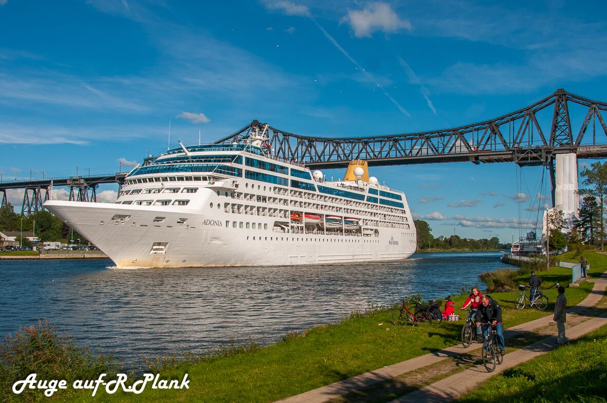 Un gran crucero amarrado en un puerto, con un puente al fondo.