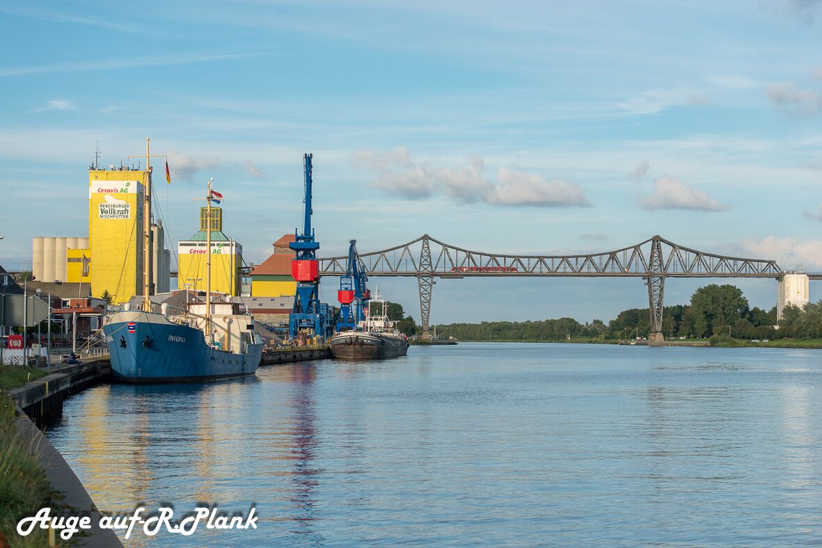 Ein Fluss mit Industriegebäuden und einer Brücke im Hintergrund.