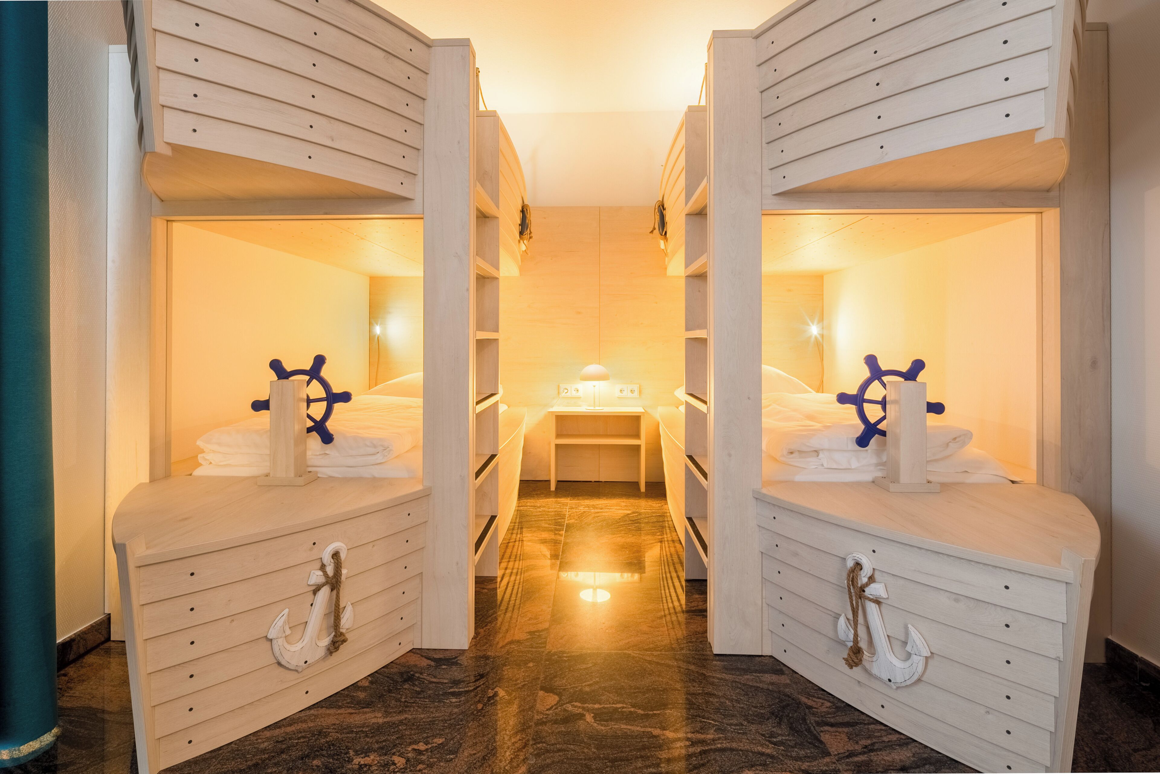 Une chambre décorée sur le thème de la marine, avec des lits superposés, un lit principal et un décor représentant un gouvernail de navire.