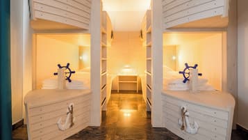 Une chambre décorée sur le thème de la marine, avec des lits superposés, un lit principal et un décor représentant un gouvernail de navire.