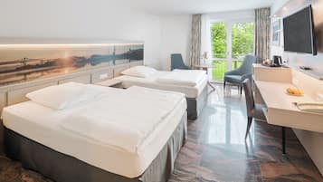 A hotel room with two beds, a desk, a chair, a TV, and a cityscape view.