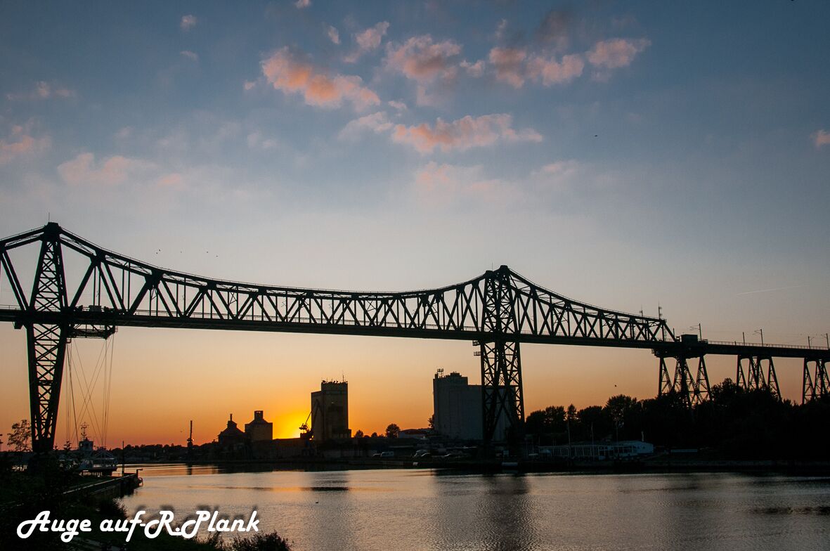 Een brug over het water, met een zonsondergang op de achtergrond.