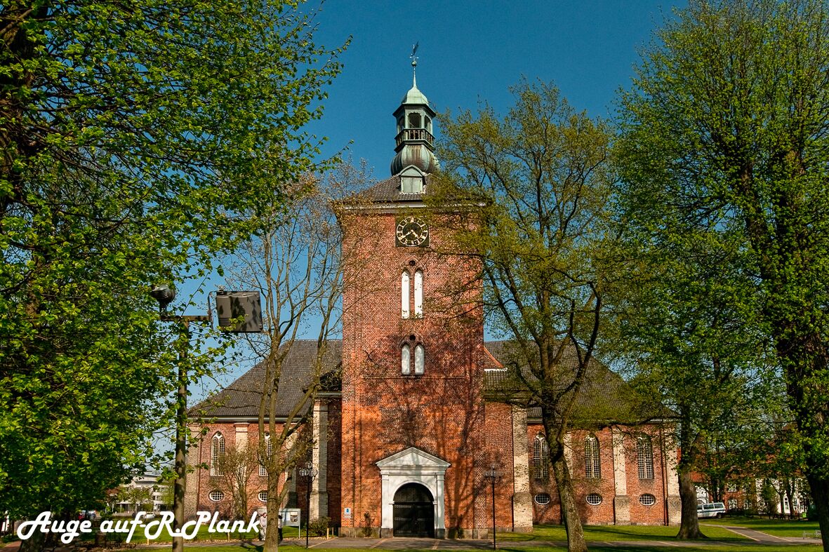 Eine historische Backsteinkirche mit einem markanten Glockenturm und Wetterfahne.