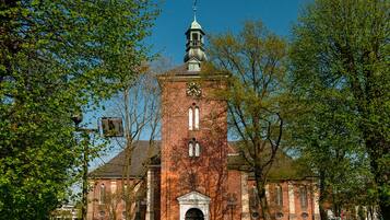 Eine historische Backsteinkirche mit einem markanten Glockenturm und Wetterfahne.