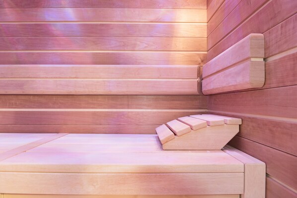 Banco de sauna de madera con respaldo inclinado y zona de asiento plana.
