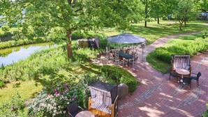 A patio area with outdoor seating, a pond, and lush greenery. - Hotel Heidehof Garni (Buedelsdorf)