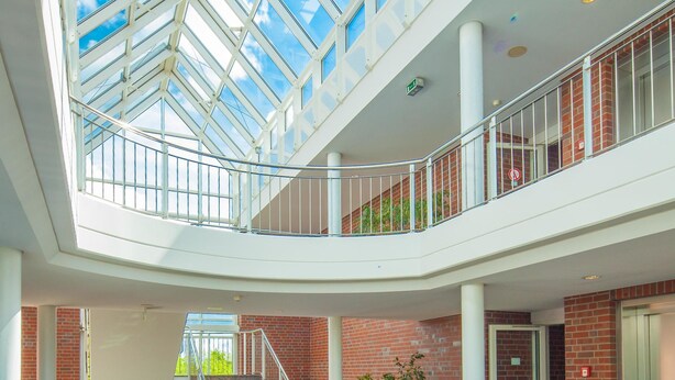 A multi-level atrium with a glass ceiling, a central staircase, and a seating area with a fireplace. - Hotel Heidehof Garni (Buedelsdorf)