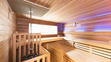 A sauna with wooden walls and benches, a ceiling light, and a clock on the wall.
