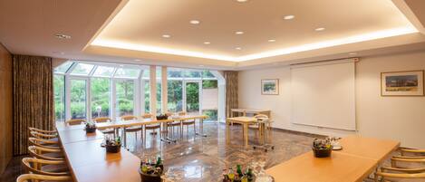 A conference room with a long table, chairs, and a projector screen.