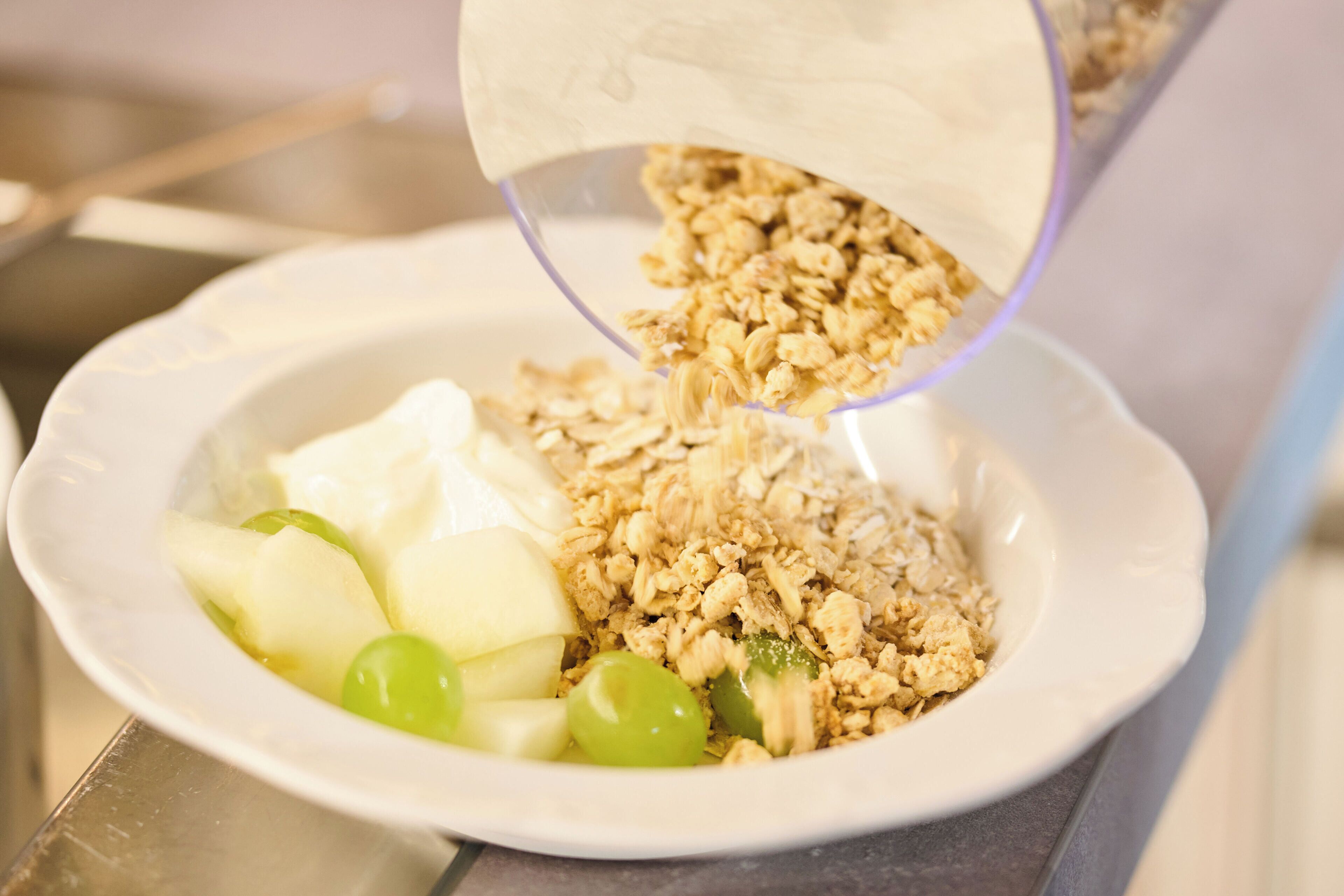 Eine Schüssel mit Joghurt, Granola und Apfel- und Traubenschnitten.