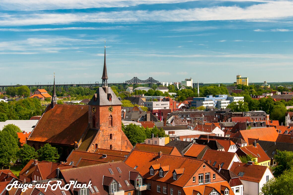Un pueblo con una imponente torre de iglesia y un puente al fondo.